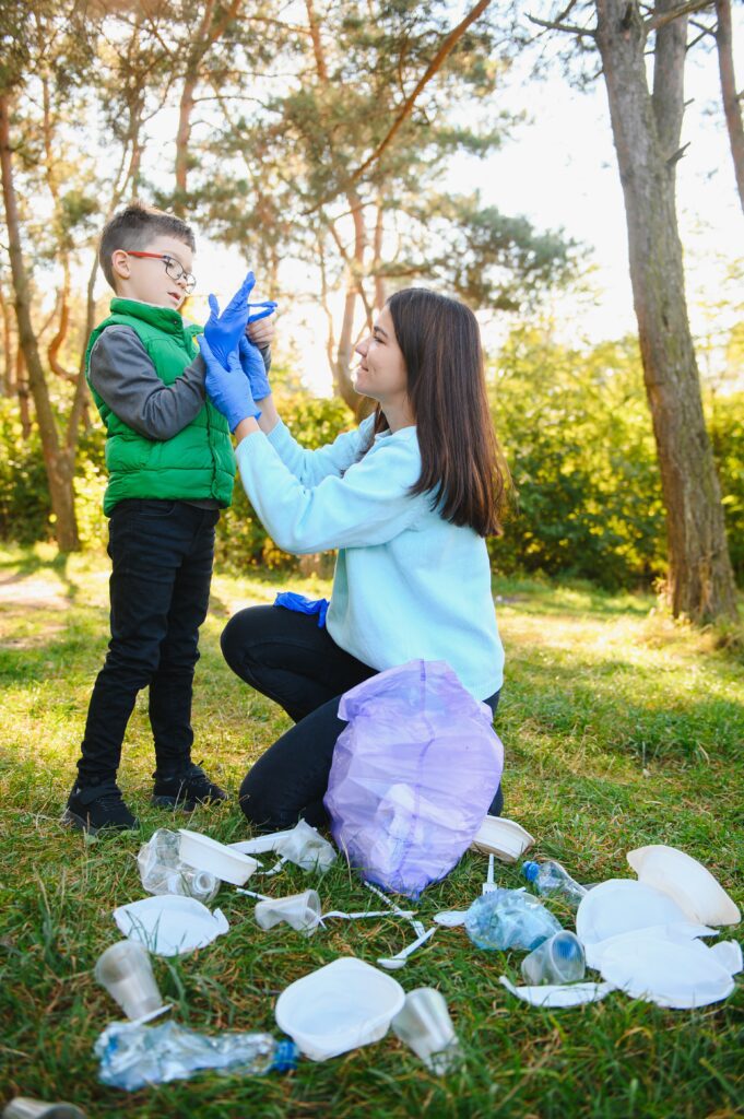 woman volunteer little boy picking up plastic garbage putting it biodegradable trash bag outdoors ecology recycling protection nature concept environmental protection
